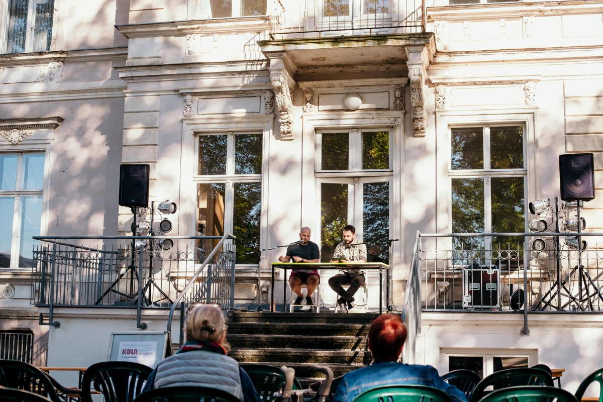 Alexander Büttner und Alexander Senf sitzen auf der Veranda des Kraftwerk Chemnitz und lesen aus AQUILERIA.